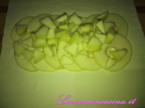 Adagiare le mele affettate e a tocchetti sul rotolo di pasta sfoglia.