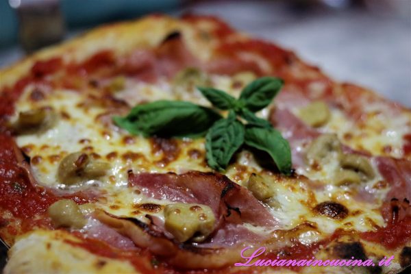 Pizza capricciosa con cotto, carciofini, funghetti e olive verdi denocciolate.