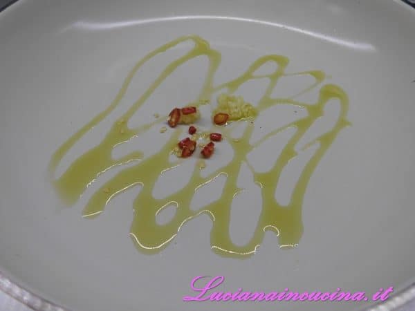 In una padella scaldare un paio di cucchiai d'olio extravergine d'oliva insieme all'aglio tritato ed al peperoncino affettato.