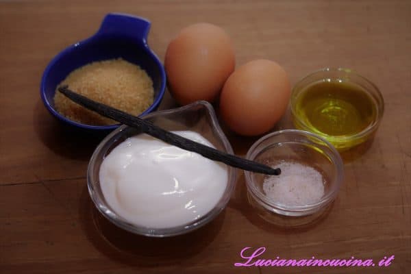 Montare in un mixer lo zucchero insieme alle uova, ai semi della bacca di vaniglia ed al sale. Poi, sempre lavorando, inserire nel mixer anche lo yogurt e l'olio a filo.