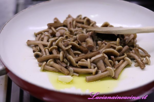 In una larga padella inserire l'olio, l'aglio e i funghi e cuocere per 10-15 minuti.