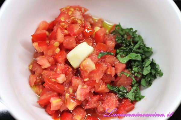 Preparare la dadolata di pomodori e aromatizzarli con uno spicchio d'aglio (che poi toglieremo), sale e basilico spezzettato.  Tenere da parte.