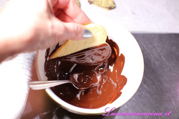 Sciogliere il cioccolato nel microonde ed intingervi i biscotti a metà, così da avere un effetto bicolore e bigusto.