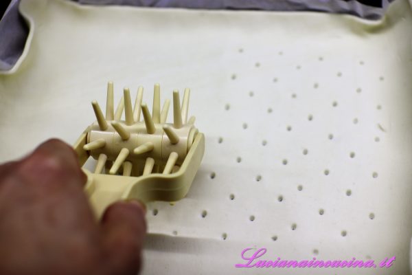 Stendere il rotolo di pasta sfoglia in una teglia rettangolare rivestita di carta forno e bucherellarla con l'apposito attrezzo oppure con i rebbi di una forchetta.