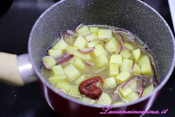 Soffriggere la cipolla tritata a julienne, aggiungere le patate , la salsa di pomodoro e portate a cottura coprendo con il brodo. A cottura raggiunta frullare