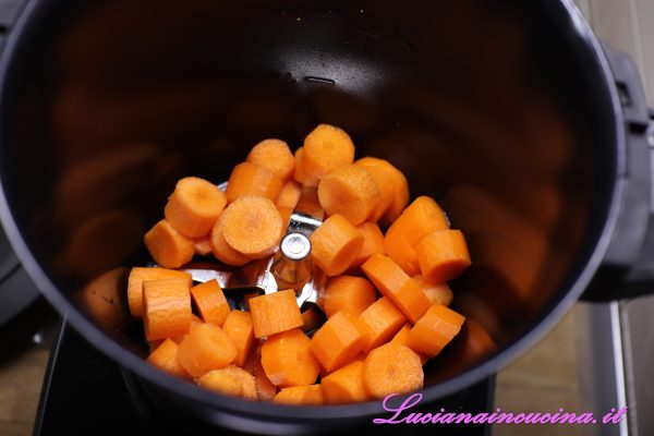 Tagliare a tocchetti le carote, inserirle nel robot da cucina con l'accessorio lame e l'interno antiaderente.